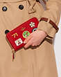 COACH®,DISNEY X COACH ACCORDION ZIP WALLET WITH PATCHES,Polished Pebble Leather,Mini,Brass/Electric Red,Detail View