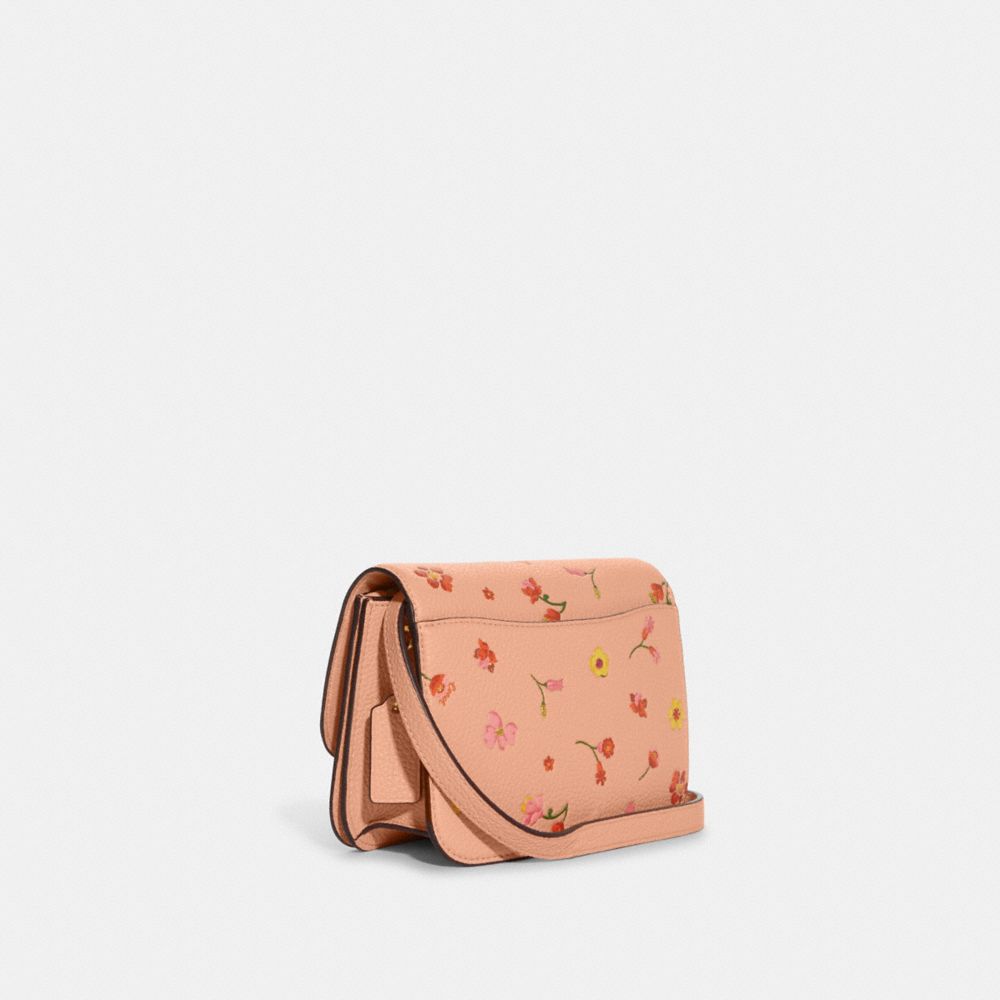 Woman holding brown and pink floral leather crossbody bag photo