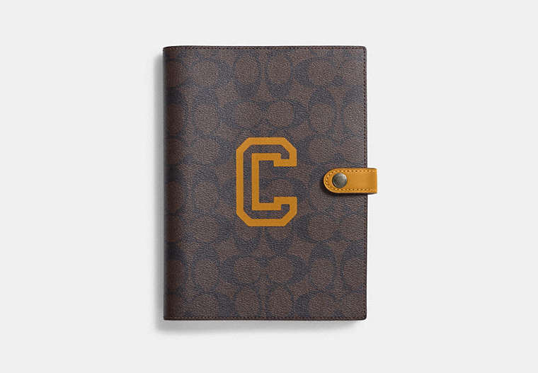 COACH®,NOTEBOOK IN SIGNATURE CANVAS WITH VARSITY MOTIF,Black Antique Nickel/Brown/Buttercup,Front View