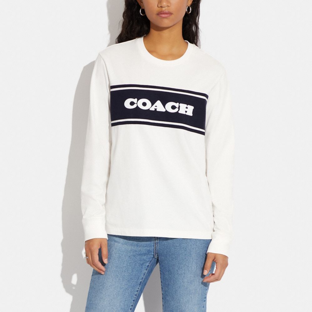 White Long Sleeved Shirt with High Top Coach Sneakers and Matching Purse