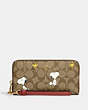 COACH®,COACH X PEANUTS LONG ZIP AROUND WALLET IN SIGNATURE CANVAS WITH SNOOPY WOODSTOCK PRINT,Signature Coated C...,Gold/Khaki/Redwood Multi,Front View