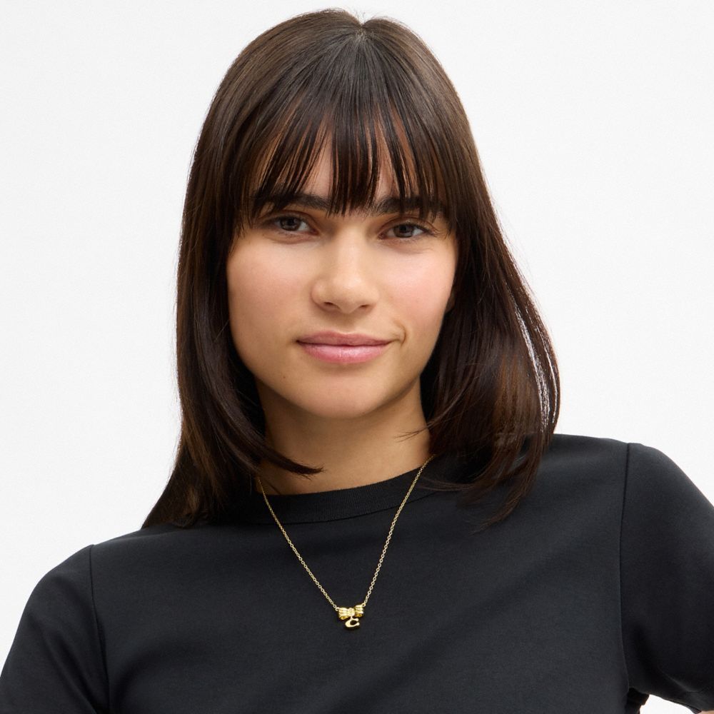 COACH®,Signature Bow Pendant Necklace,Single Strand,Glass,Cubic Zirconia,Initials Embellishment,Lettering Word,Logo,Bow,Ge...,Yellow,Detail View