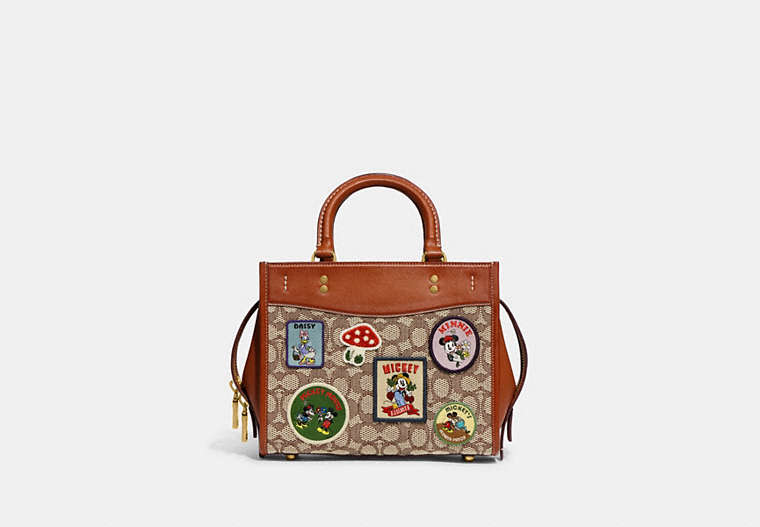 COACH®,DISNEY X COACH ROGUE 25 IN SIGNATURE TEXTILE JACQUARD WITH PATCHES,Jacquard,Medium,Brass/Cocoa Burnished Amber Multi,Front View