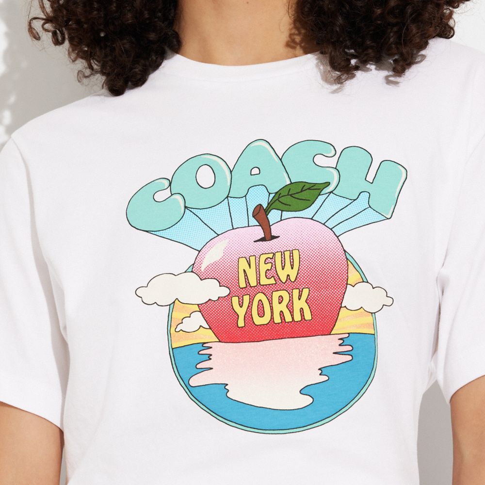 公式】COACH – コーチ | ニューヨーク アップル サンセット Tシャツ
