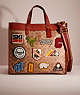 COACH®,RESTORED FIELD TOTE 40 IN SIGNATURE CANVAS WITH PATCHES,Signature Coated Canvas,Large,Brass/Tan,Front View