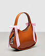 COACH®,Ergo Bag in Crinkle Patent Coachtopia Leather with Bows,Burnished Amber/Light Pink,Angle View