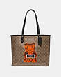 COACH®,REVERSIBLE CITY TOTE IN SIGNATURE CANVAS WITH VANDAL GUMMY,pvc,Large,Gold/Khaki Multi Black,Front View